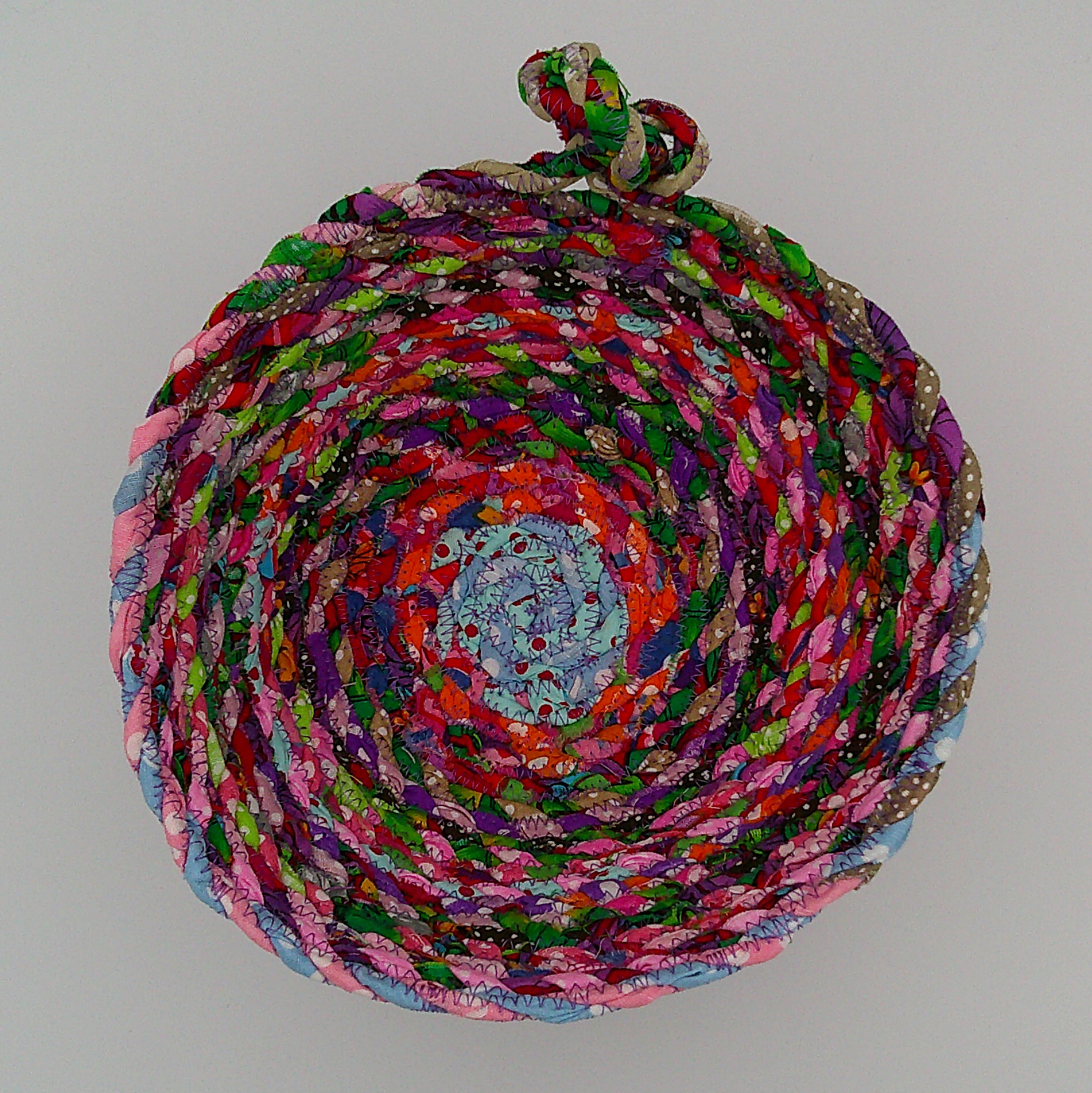 This view is looking down into the fabric rope basket. It shows the variety of all the scraps used to make the rope which made the basket. This view is looking down into the fabric rope basket. It shows the variety of all the scraps used to make the rope which made the basket.